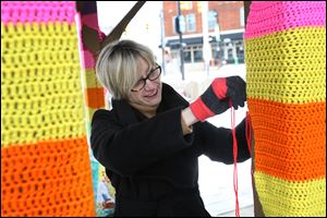 Michelle Atkinson puts the finishing touches Tuesday on the crocheted yarn enveloping the posts of the gazebo near the downtown. Ms. Atkinson spearheaded the project, organized with the Sylvania Community Arts Commission’s blessing. Ms. Atkinson said she hopes to make it an annual event.