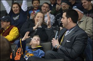 Walleye announcer Anthony Bellino, right, high fives Connor Wright, 4, during a recent game. The 2010 Bowling Green State University graduate is in his first season with the Walleye.
