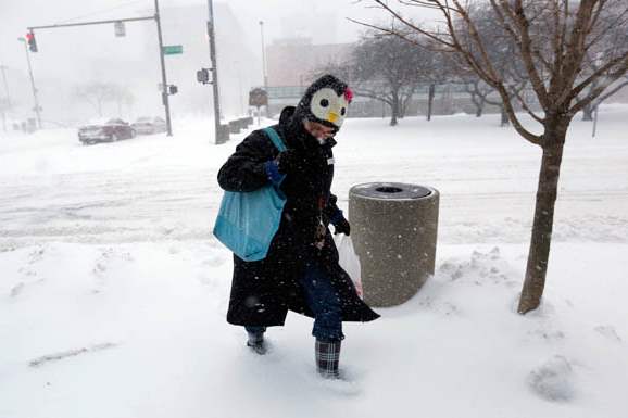 Julie-Bellman-wearing-a-penguin-hat-trudges-through-accumulating-snow-as