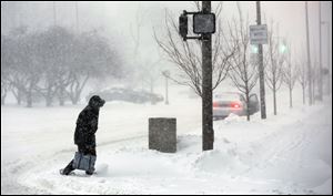 A pedestrian crosses Jackson Street at North Huron Street during a snowstorm today.