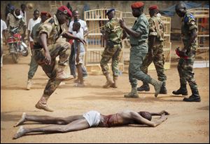 A  FACA (Central African Armed Forces) officer jumps on the lifeless body of a suspected Muslim Seleka militiaman moments after Central African Republic Interim President Catherine Samba-Panza addressed the troops.