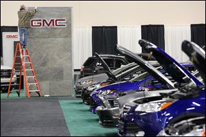 The GMC sign receives a final polishing as part of the preparation for today’s opening of the Toledo Auto Show at SeaGate Convention Centre. A line of Ford vehicles sits at the right.