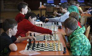 Evan Metz, 8, reaches across his board to make a move during the Central Trail Elementary chess club practice in the school library. The teams’ first match is March 7 against Ottawa Hills Elementary. School.