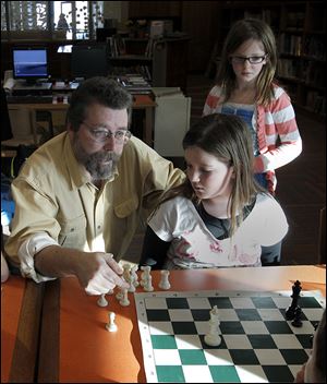 Coach Jim Van Vorhis teaches Zoe Kyle, 9, some of the finer points of the game of chess.