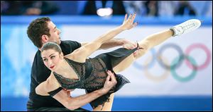 U.S. figure skaters Simon Shnapir and Marissa Castelli perform at the Iceberg Skating Palace in Sochi, Russia. Meanwhile, Russian President Vladimir Putin seems unruffled by a storm of major and minor criticism.