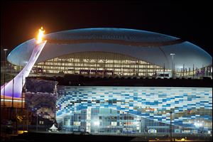 The Olympic Cauldron, left, is lit during a test between the Bolshoy Ice Dome, top, and the Iceberg Skating Palace, foreground, early today.