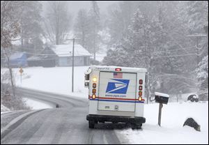 A U.S. Postal Service vehicle delivers mail during a light snowfall in Nassau, N.Y. in January.