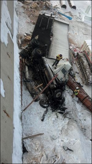 Crews examine the damaged truck early today that fell off the I-475 overpass Thursday night.