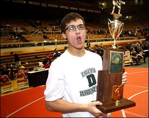 Delta High School wrestler Christian Valentine gets the championship trophy following the team's win over Dayton Christian.