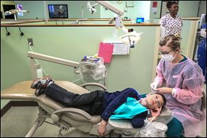 Isaac Truman, 9, waits for dental hygiene student Jen Donaldson to resume cleaning his teeth at Owens’ clinic. Student volunteers outnumbered those already in practice.