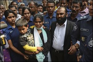 Two owners of Tazreen Fashions Ltd., Delwar Hossain, center left, and his wife, Mahmuda Akter, right, are escorted by security personnel on Sunday to a court in Dhaka, Bangladesh. The owners of a Bangladesh garment factory where 112 workers died in a fire two years ago surrendered on Sunday and sought bail after they were charged with homicide.