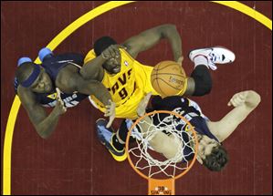 The Cavaliers' Luol Deng, center, shoots between Memphis Grizzlies defenders Zach Randolph, left, and Marc Gasol on Sunday night in Cleveland.
