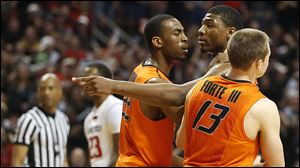 Oklahoma State's Markel Brown, left, and Phil Forte, right, hold Marcus Smart after Smart shoved a fan during their game Saturday night in Lubbock, Texas.