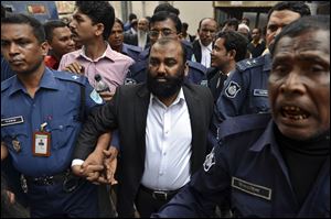 One of the two owners of Tazreen Fashions Ltd., Delwar Hossain, center, is escorted by security personnel Sunday to a court in Dhaka, Bangladesh.