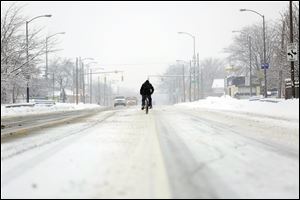 A bicycle rider braves a fresh blanket of snow during a Sunday drive down the middle of Summit Street.