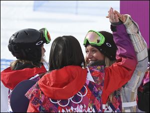 Jamie Anderson of the United States, right celebrates with Switzerland's Sina Candrian, center, and Britain's Jenny Jones, left, after Anderson won the women's snowboard slopestyle final.