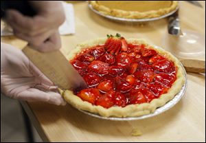 A strawberry pie is cut.