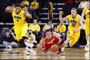 Ohio State’s Aaron Craft dives for the ball between Iowa's Roy Devyn Marble, left, and Mike Gesell. The Buckeyes have won three games in a row after losing five of six. OSU hosts Michigan today.