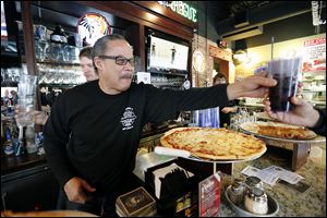 Retired Toledo Firefighter Steve Jones works the bar during a one-day fund-raiser Monday to benefit the Toledo Fire and Rescue Foundation at PizzaPapalis in Toledo.