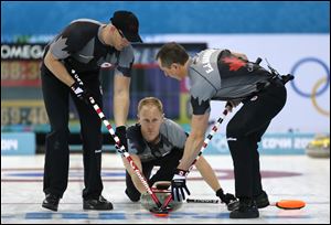 Canada's skip Brad Jacobs, center, delivers the rock to his sweepers Brian Harndin, left, and E. J. Harnden.