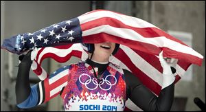 Erin Hamlin of the United States celebrates with the American flag after finishing her final run to win the bronze medal in the women's singles luge competition at the 2014 Winter Olympics.