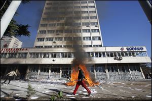 A Bosnian protester walks past a local government building during protests in Tuzla, Bosnia. 