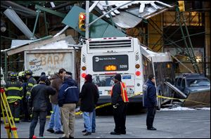 A Metropolitan Transportation Authority bus and a truck rest against scaffolding at 14th Street and 7th Avenue in New York, today, after an early morning collision between the bus and truck. One person was killed and at least four were injured in the crash.