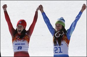 Women's downhill gold medalists Switzerland's Dominique Gisin, left, and Slovenia's Tina Maze, right, hold hands during a flower ceremony today.