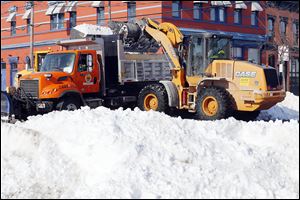 City workers clear snow at South St. Clair and Lafayette streets in downtown Toledo during record-cold temperatures Wednesday.