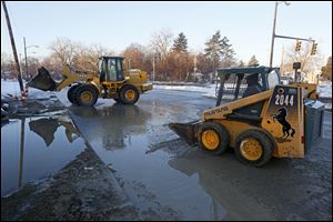 Crews clear water and ice from the Anthony Wayne Trail near Glendale Avenue in Toledo following a water main break early today.