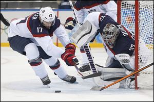 American forward Ryan Kesler, left, and goaltender Jonathan Quick defend against a shot against Slovakia during their first hockey game in Sochi, Russia. The United States rolled 7-1.