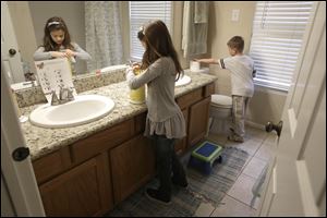 Lily Cherry, 8, cleans her bathroom as her brother Aiden, 6, right, puts out a new roll of toilet paper at their home in Kingwood, Texas. Their mother, Andrea Cherry, has passed on her childhood practice of doing chores to her children, believing it gives them a sense of family responsibility.
