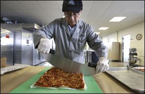 In this Thursday, Feb. 6, 2014 photo, food technologist Tom Yang cuts a prototype pizza at the U.S. Army Natick Soldier Research, Development and Engineering Center, in Natick, Mass. 