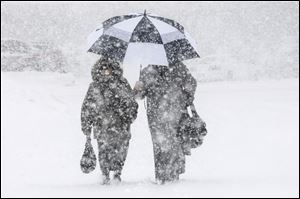 Shoppers make their way through heavy snow after shopping at the Big  Y supermarket on Memorial Drive  in Chicopee, Mass.,  Thursday.