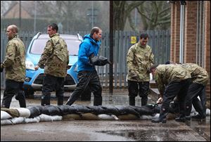 Britain's Prince William, The Duke of Cambridge, center, unloads sandbags, with members of the armed forces on Friday in Datchet, England.
