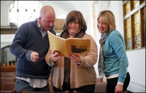 From left: Mike McArthur, Heather Meyer, and Lori Reid look at a 1970-1971 yearbook of the congregation.