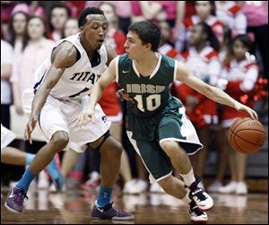 Central Catholic’s Andrew Grombacher drives against Anthony Glover, Jr., of St. John’s, who finished with 20 points.