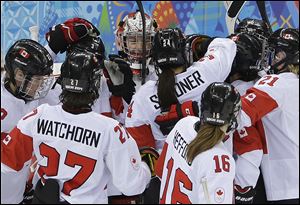 Goalkeeper Shannon Szabados of Canada is surrounded by teammates after Canada's 3-1 win over Switzerland in a 2014 Winter Olympics women's semifinal game at Shayba Arena, Monday in Sochi, Russia.