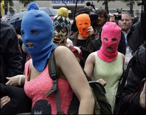 Russian punk group Pussy Riot members Nadezhda Tolokonnikova, in the blue balaclava, and Maria Alekhina, in the pink balaclava, make their way through a crowd after they were released from a police station, today in Adler, Russia.