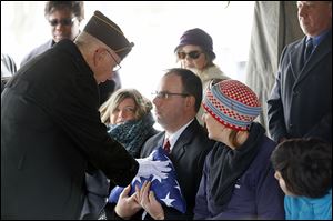 Cmdr. Terry Mohler of the Lucas County Veterans Burial Corps gives the flag that had been on the casket of Joseph John Patay to his son Joseph, Jr., during the funeral at Mount Carmel Cemetery.