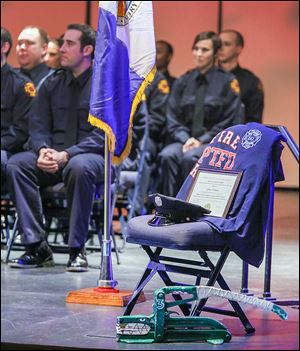 An empty chair marks the absence of firefighter James Dickman during a graduation ceremony for the Toledo Fire Department at the University of Toledo’s Doermann Theatre. Mr. Dickman died in the line of duty on Jan. 26.
