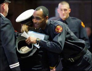 Pvt. Antwoine Mister hugs Battalion Chief Sally Glombowski after receiving his hat during a graduation ceremony for the Toledo Fire Department. Private Mister was among 47 new firefighters who graduated on Friday.