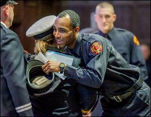 Pvt. Antwoine Mister hugs Battalion Chief Sally Glombowski after receiving his hat during a graduation ceremony for the Toledo Fire Department. Private Mister was among 47 new firefighters who graduated on Friday.