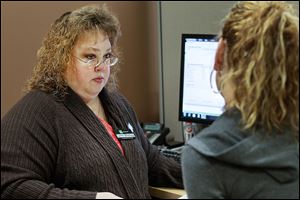 Lynn Bishop of Toledo, a tax specialist with H & R Block in Holland, helps a client prepare her taxes.