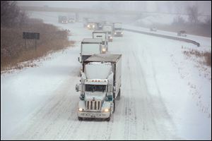 Trucks slowly move north on I-75 near Summit Street in Erie Township, Michigan, as snow hammers the area on Feb. 5. Ice, snow, wind, and potholes have made driving a white-knuckle event.