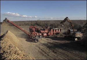 A crew from G&F Agri Service LLC uses heavy equipment to remove an almond orchard and to turn the trees into wood chips at Baker Farming Company in Firebaugh, Calif.