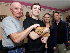 From left, Kyle Ford, Ryan Golden, Shae Golden, and Kris Hepperly adopted Piper, who is doing well now. When freed from the drain, Piper was emaciated and hypothermic from his ordeal. He also had a broken leg and a little frostbite.