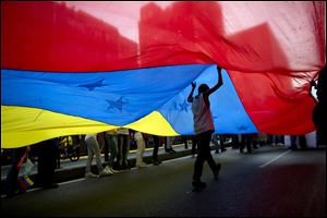 A youth walks under a large Venezuelan flag during a rally organized by workers of the National Telecommunications Company or CANTV to show support for the government.