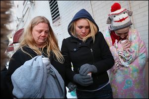 Tracy Bishop, left, her daughter Emily, center, and Elizabeth Mabe pray together during a vigil for firefighters Stephen Machcinski and James Dickman at Magnolia and Huron streets in North Toledo. Ms. Bishop had lived at the site of the fatal fire.