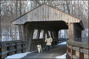 Scott Montri of West Toledo walks his goldendoodle, Woody, in Wildwood Preserve Metropark, where the boardwalk and covered bridge that cross the Ottawa River will be rebuilt. 